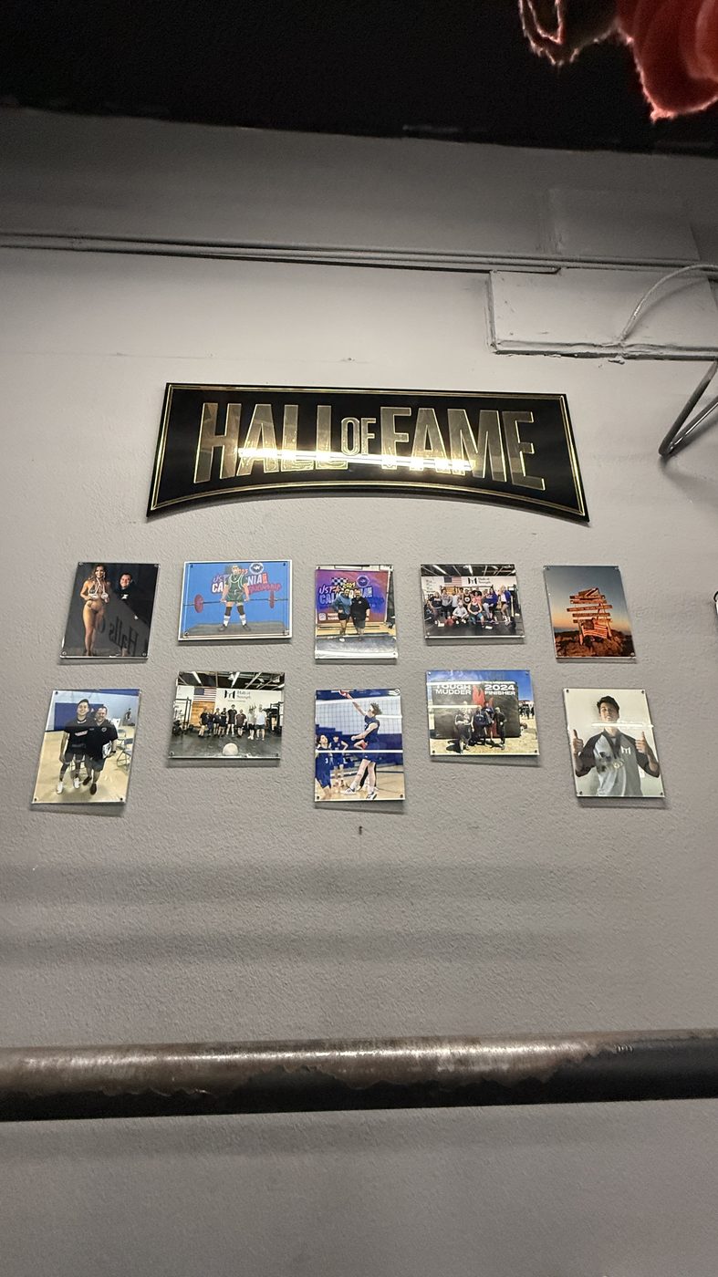 The Hall of Fame wall at Halls of Strength, framed photos of members under the sign